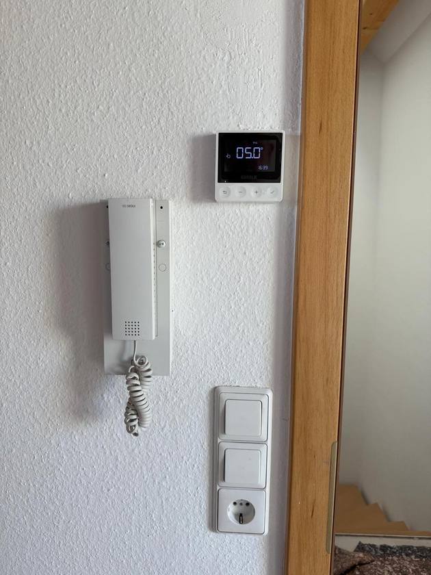 Raumthermostat neben einer Türsprechanlage und Lichtschaltern in Biberach.