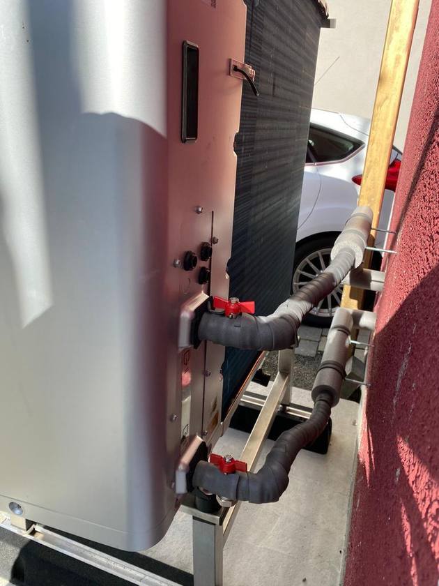 Außeneinheit einer Wärmepumpe mit Leitungsanschlüssen am Installationsort.